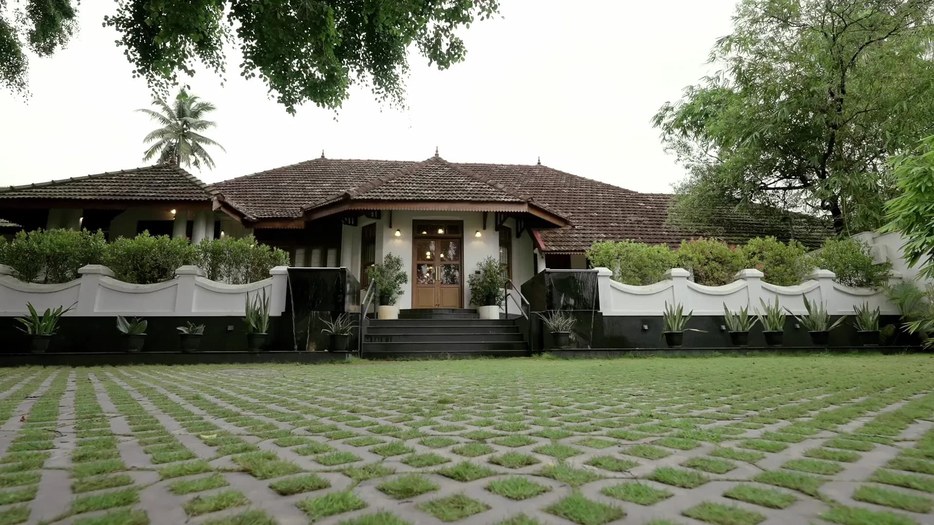 The Amritha Heritage bungalow seen across its lawn, the tiled roof and white verandah framed by old trees.