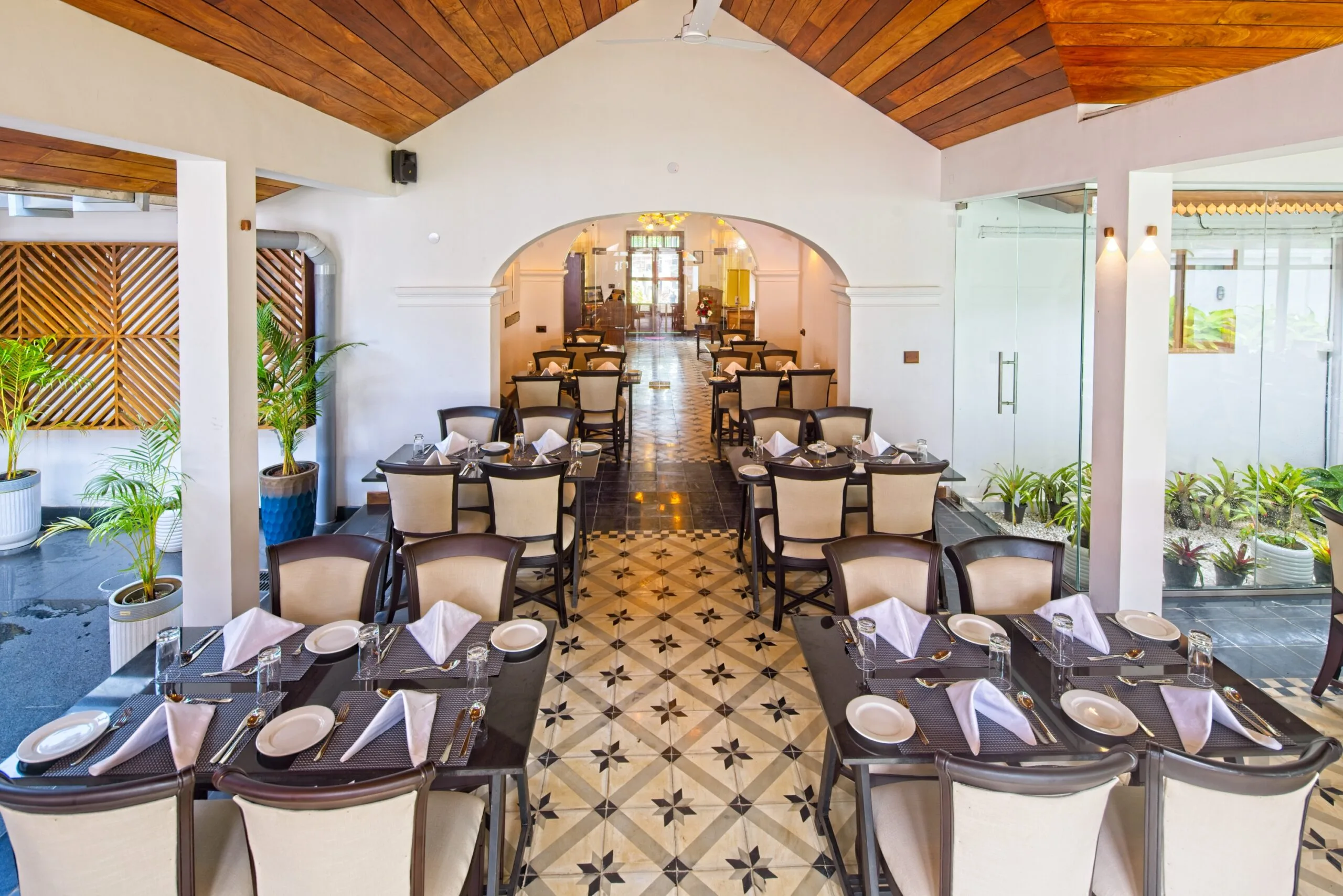 Laid tables receding through an arched opening into the far dining room.