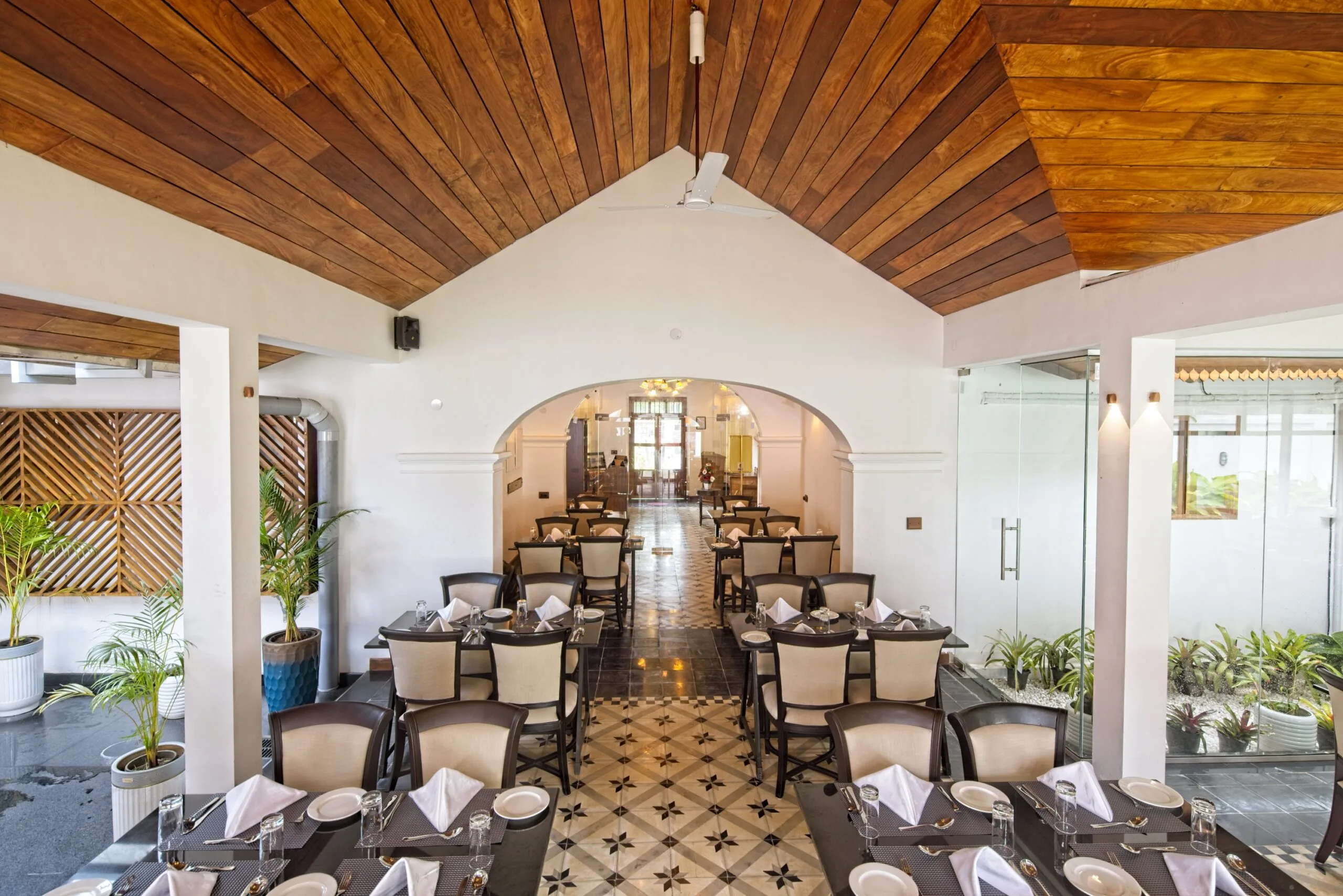 The dining room with potted palms along the wall and a patterned tile floor.