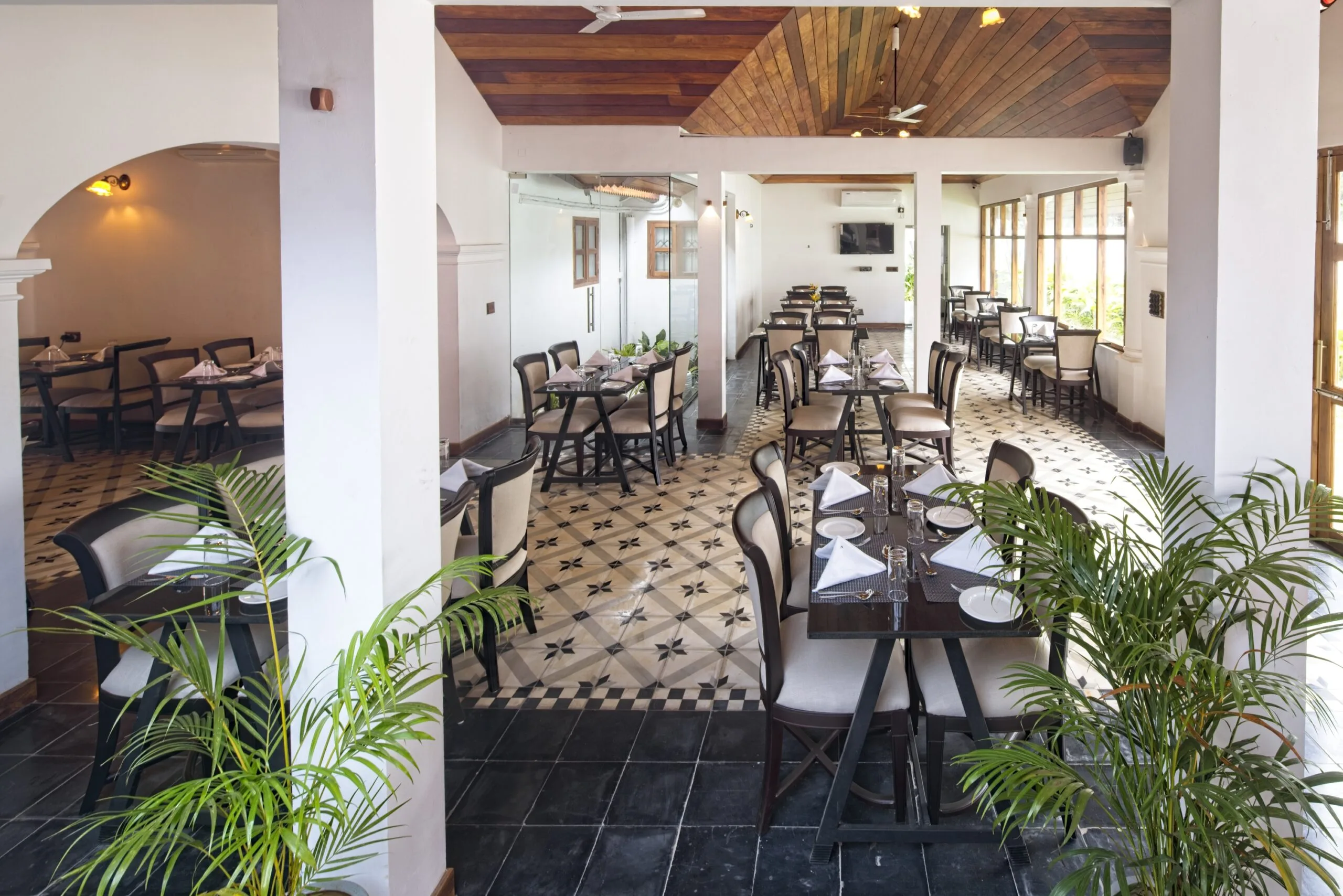 The dining room seen along its length, tables set between white columns.