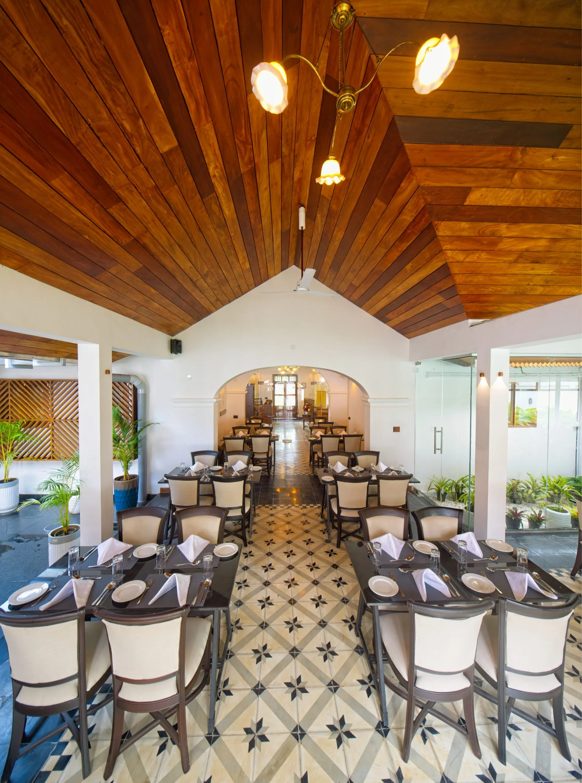 The dining room under a vaulted teak ceiling, tables laid along a star-patterned tile floor.